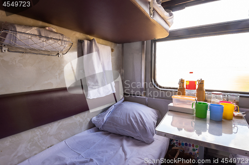 Image of Empty bottom bunk in a reserved seat carriage and table with dishes