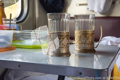 Image of Empty glasses in metal cup holders stand on a table in a train compartment