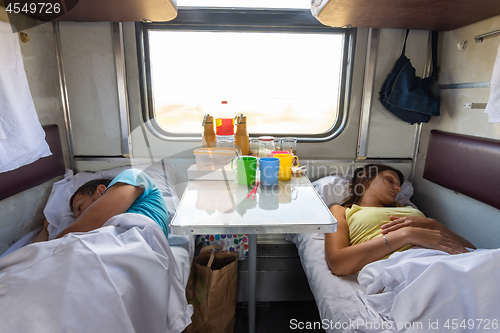 Image of Man and woman sleep on lower shelves in a train car