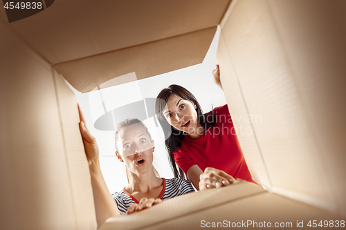 Image of Women unpacking and opening carton box and looking inside