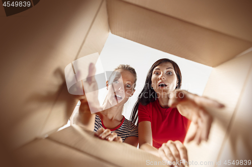 Image of Women unpacking and opening carton box and looking inside