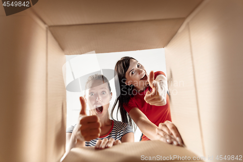 Image of Women unpacking and opening carton box and looking inside