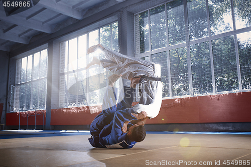 Image of Two judo fighters showing technical skill while practicing martial arts in a fight club