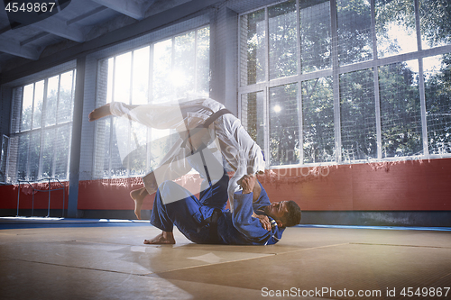 Image of Two judo fighters showing technical skill while practicing martial arts in a fight club