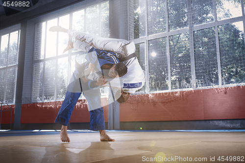 Image of Two judo fighters showing technical skill while practicing martial arts in a fight club