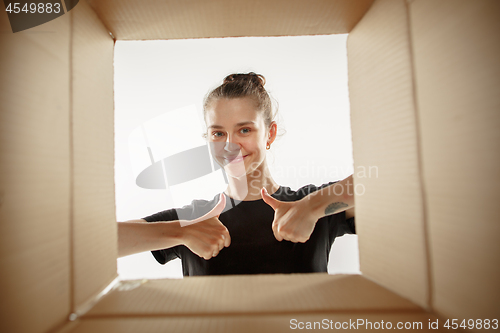 Image of Woman unpacking and opening carton box and looking inside