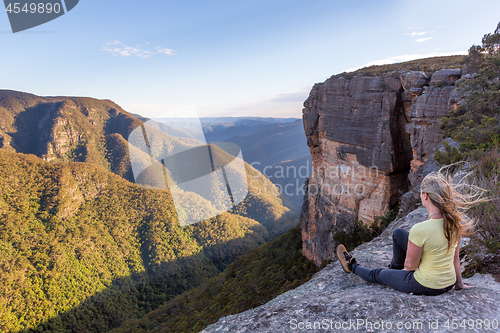 Image of Woman takiong in beautiful mountain views from cliff top lookout