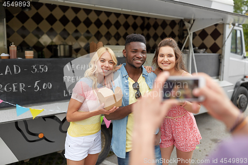 Image of man taking picture of friends eating at food truck