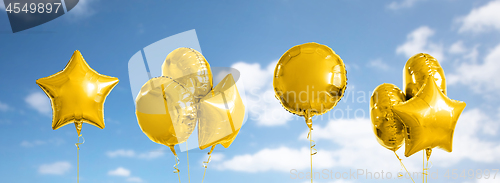 Image of many metallic gold helium balloons on white