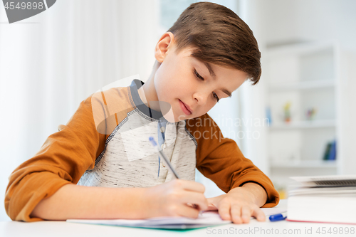 Image of boy doing homework and writing to notebook at home