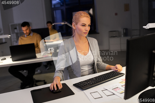 Image of designer working on computer at night office