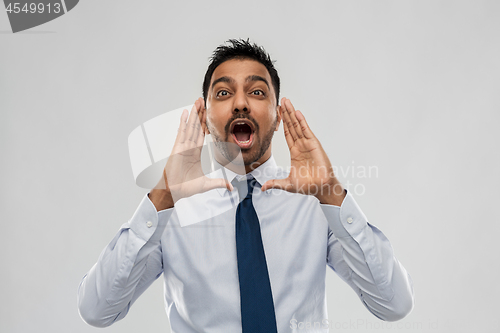 Image of indian businessman shouting or calling over grey