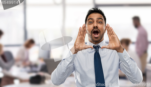 Image of indian businessman shouting or calling over office