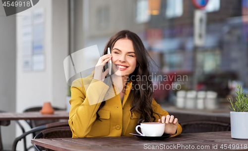 Image of teenage girl calling on smartphone at city cafe