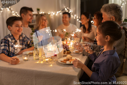 Image of family with sparklers having dinner party at home