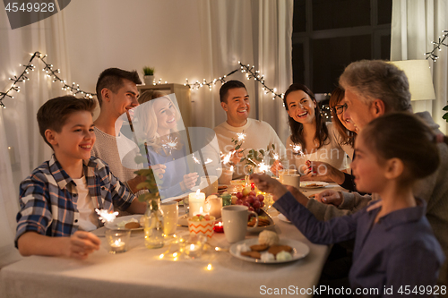 Image of family with sparklers having dinner party at home