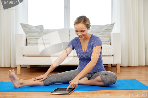 Image of woman with tablet computer doing yoga at home