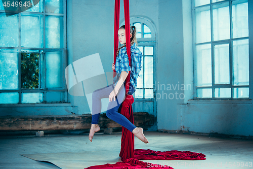 Image of Graceful gymnast performing aerial exercise at loft