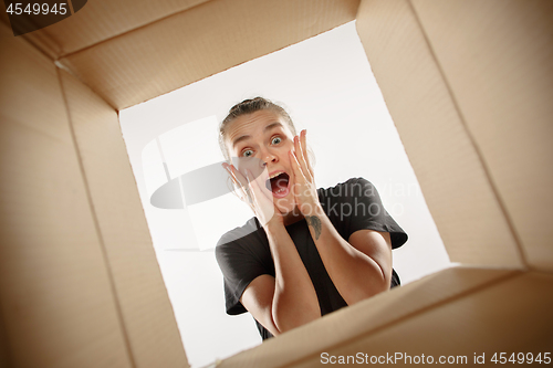 Image of Woman unpacking and opening carton box and looking inside