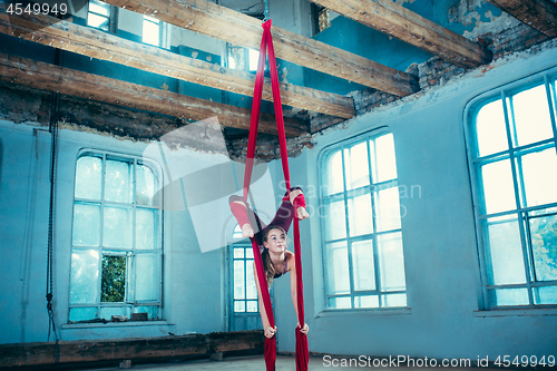 Image of Graceful gymnast performing aerial exercise at loft