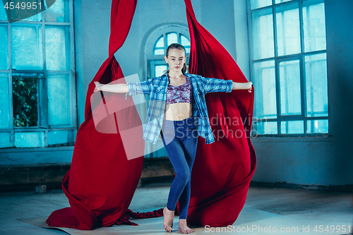 Image of Graceful gymnast resting after performing aerial exercise at loft