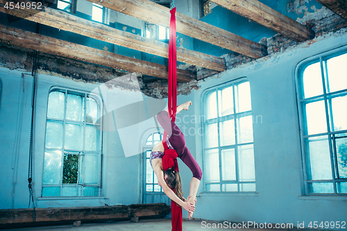 Image of Graceful gymnast performing aerial exercise at loft