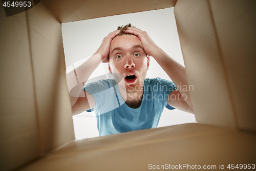 Image of Man smiling, unpacking and opening carton box and looking inside