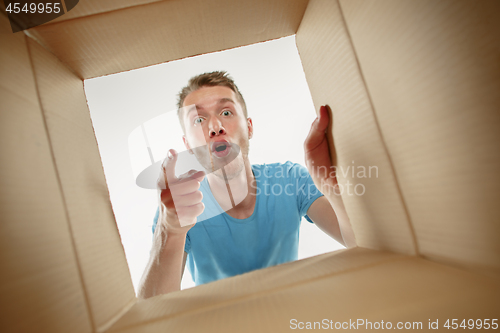 Image of Man smiling, unpacking and opening carton box and looking inside