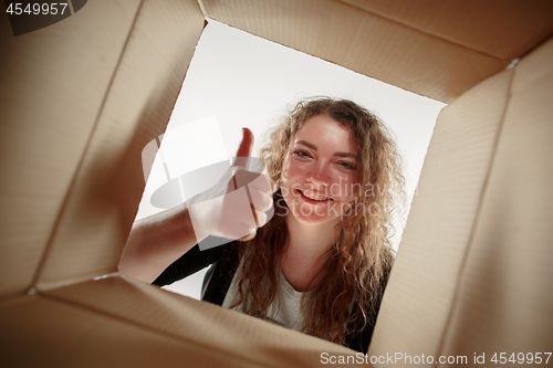 Image of Woman unpacking and opening carton box and looking inside