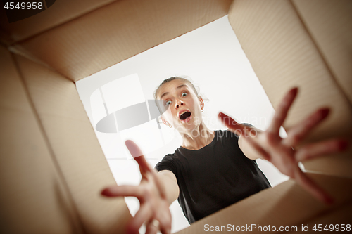 Image of Woman unpacking and opening carton box and looking inside