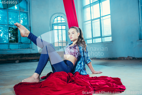 Image of Graceful gymnast resting after performing aerial exercise at loft