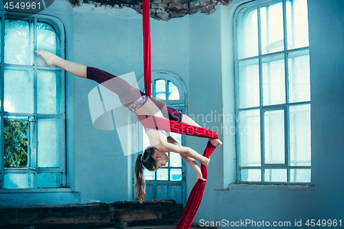 Image of Graceful gymnast performing aerial exercise at loft