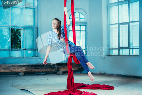 Image of Graceful gymnast performing aerial exercise at loft