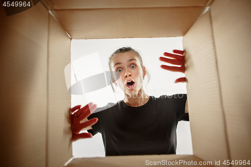 Image of Woman unpacking and opening carton box and looking inside