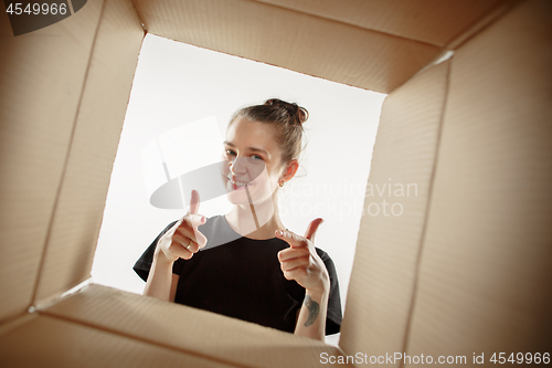 Image of Woman unpacking and opening carton box and looking inside