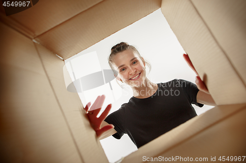 Image of Woman unpacking and opening carton box and looking inside