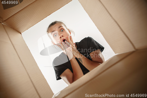 Image of Woman unpacking and opening carton box and looking inside