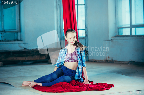 Image of Graceful gymnast resting after performing aerial exercise at loft