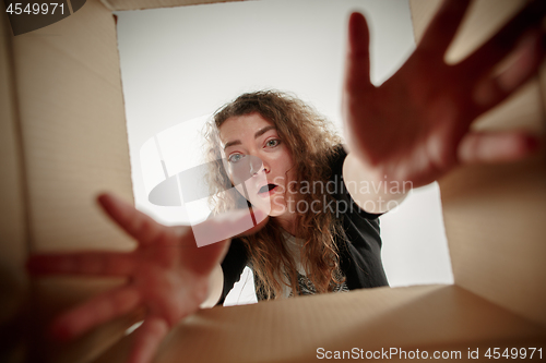 Image of Woman unpacking and opening carton box and looking inside