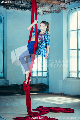 Image of Graceful gymnast performing aerial exercise at loft