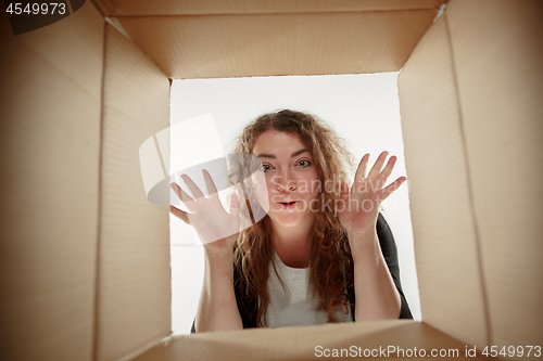 Image of Woman unpacking and opening carton box and looking inside