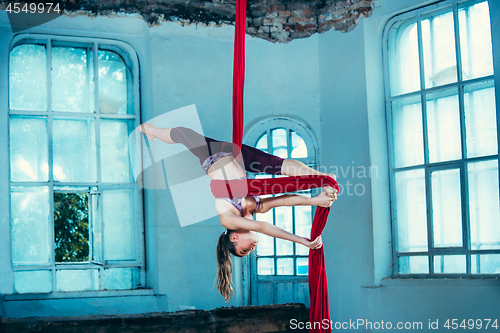 Image of Graceful gymnast performing aerial exercise at loft