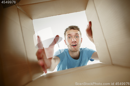 Image of Man smiling, unpacking and opening carton box and looking inside