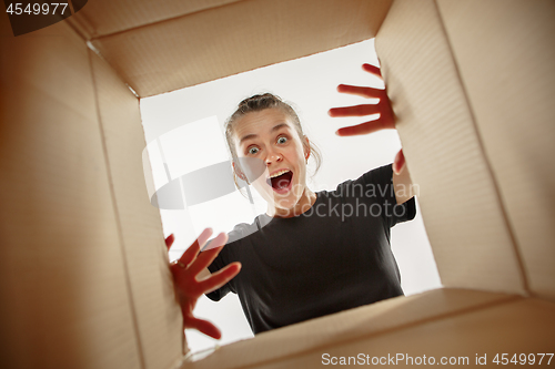 Image of Woman unpacking and opening carton box and looking inside