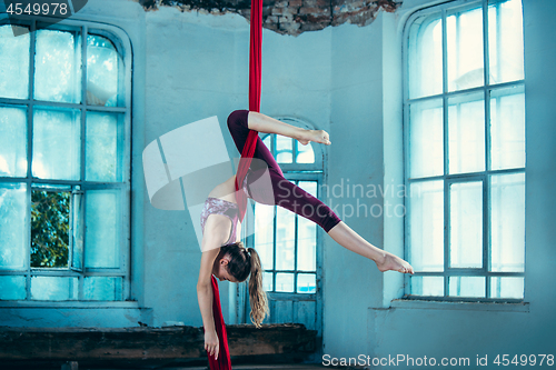 Image of Graceful gymnast performing aerial exercise at loft