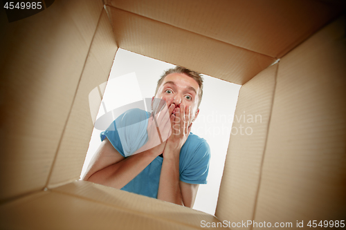 Image of Man smiling, unpacking and opening carton box and looking inside