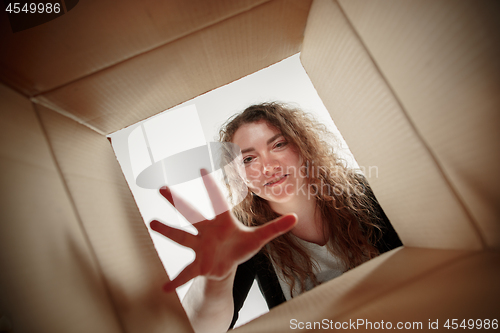 Image of Woman unpacking and opening carton box and looking inside