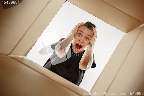 Image of Woman unpacking and opening carton box and looking inside