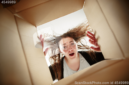 Image of Woman unpacking and opening carton box and looking inside