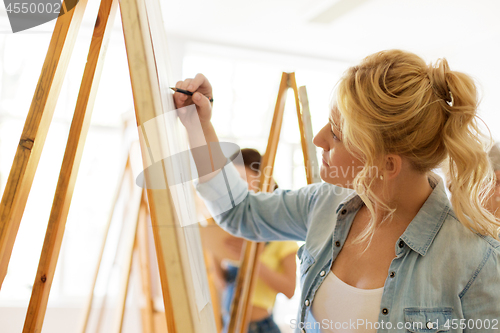 Image of woman with easel drawing at art school studio